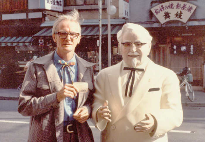 William Lipscomb in Japan holding his Kentucky Colonel card by a statue of Colonel Sanders